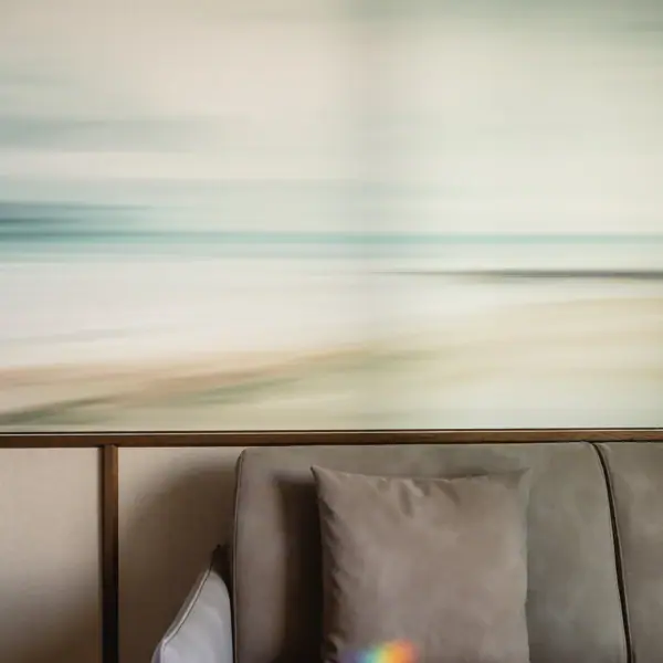 Sofaecke Couch mit Kissen vor einem unscharfen Strandbild an der Wand.