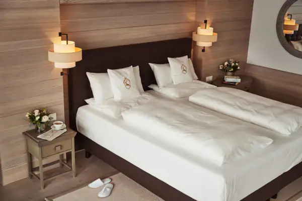 Zimmer Ein Bett mit weißen Laken und Kissen.