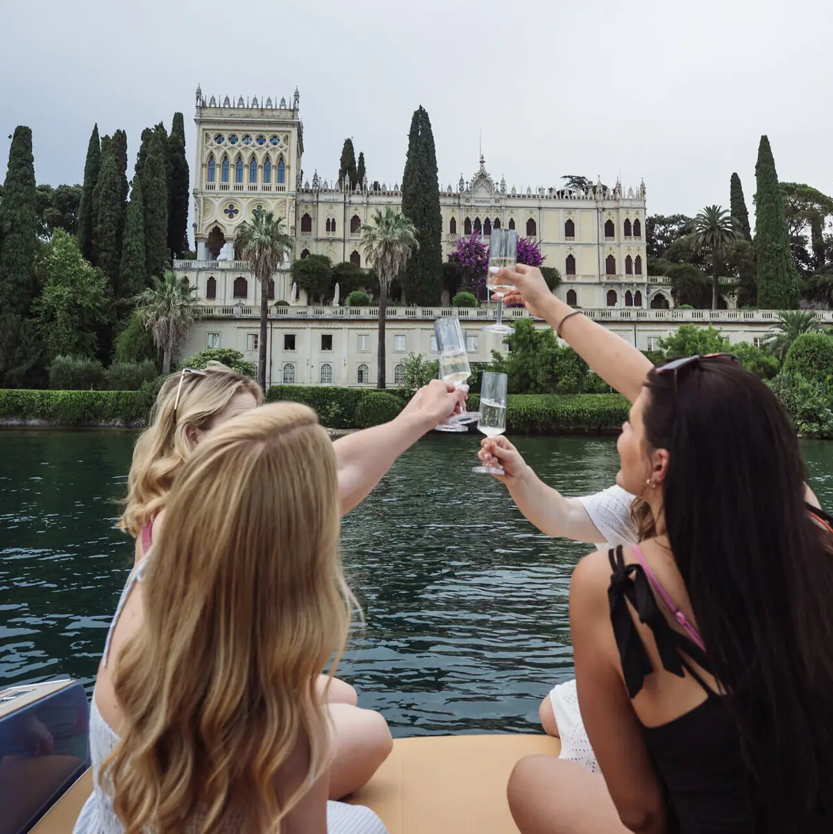 Eine Gruppe von Frauen hält Weingläser vor einem Schloss.