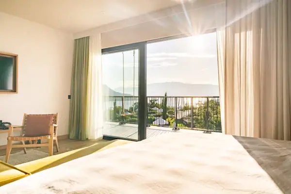 Zimmerausblick Ein Zimmer mit einem Bett und einem Balkon mit Blick auf das Meer.