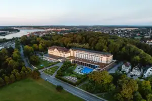 A-ROSA Travemünde Großes Gebäude mit Pool, umgeben von Bäumen.