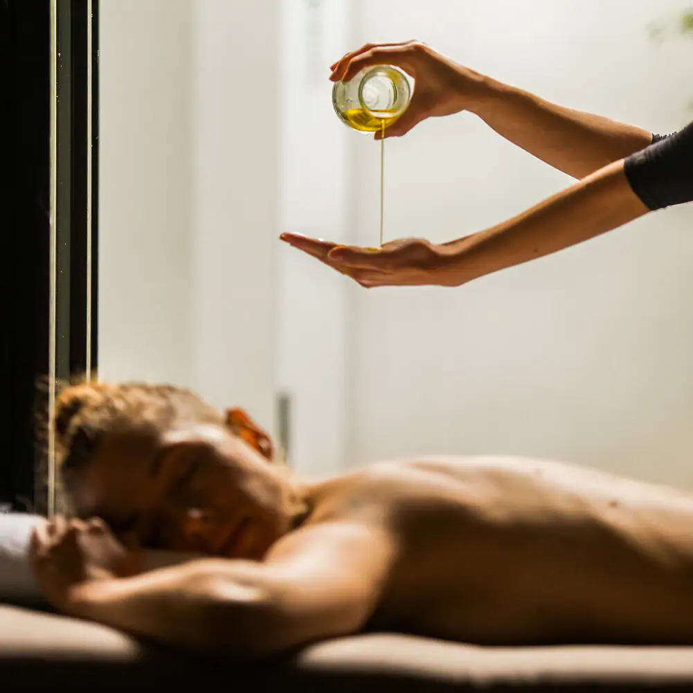 SPA-Menü Eine Person gießt Öl in die Hand einer anderen Person.