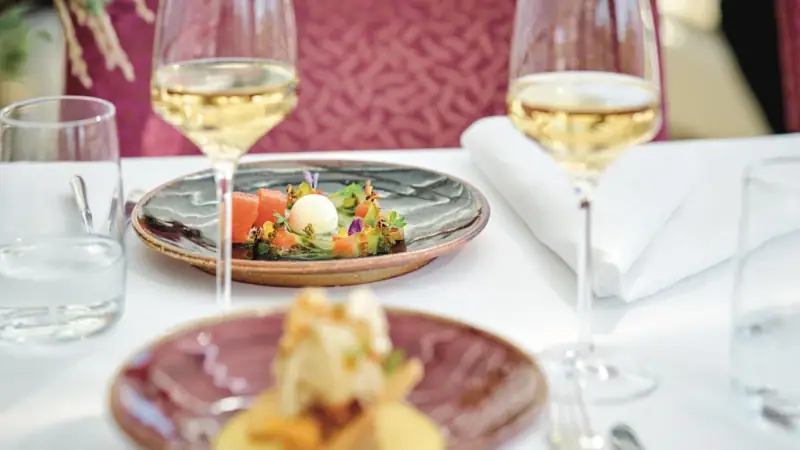 Ein Teller mit Essen auf einem Tisch mit Weingläsern.