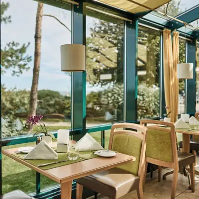 Ein Tisch mit Stühlen und Servietten in einem Raum mit Fenstern.