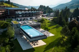 A-ROSA Ifen Hotel Kleinwalsertal Ein Außenpool in einem Hotel, umgeben von Bäumen und einem klaren Himmel.