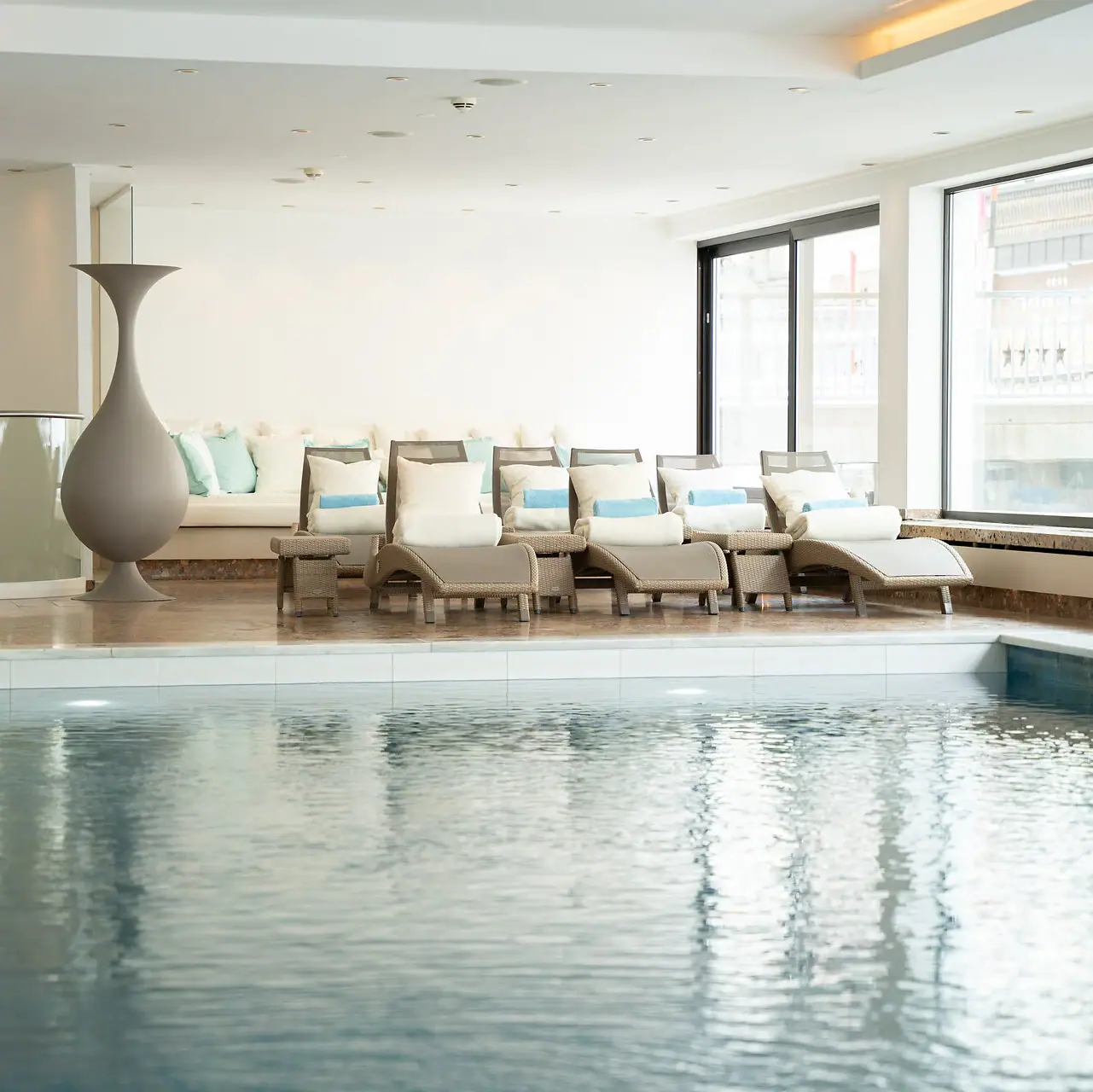 Ein Pool mit einem großen Vase und Stühlen im Innenbereich.