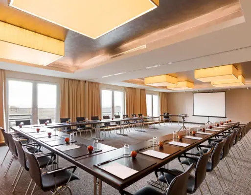 Konferenzraum Ein großer Konferenzraum mit Tischen und Stühlen.