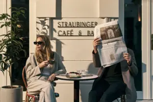 Café & Bar Ein Mann und eine Frau sitzen an einem Tisch und lesen eine Zeitung.