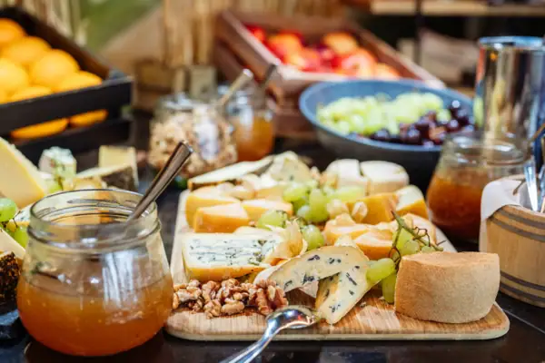 Buffett Travemünde Auf einem Buffett steht ein Holzbrett verschiedenen Käsesorten, Weintrauben und Feigensenf.