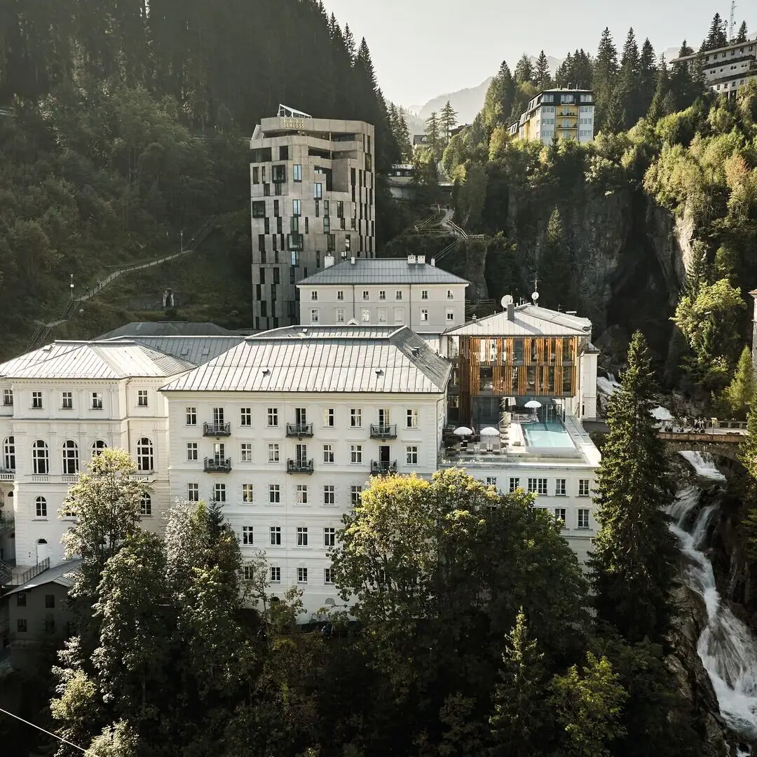 Eine Gruppe von Gebäuden mit Bäumen und Bergen im Hintergrund.