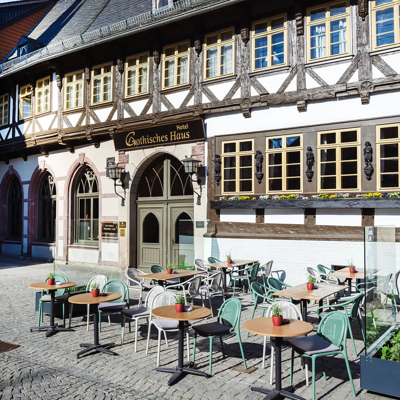 Gothisches Haus Wernigerode Ein Gebäude mit Tischen und Stühlen im Freien.
