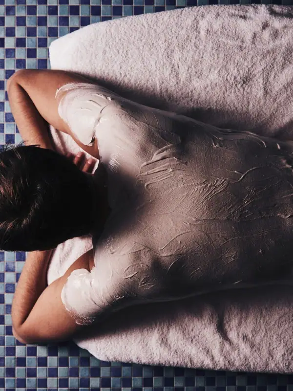 Eine Person liegt auf einem Handtuch mit einem weißen Körperwickel.