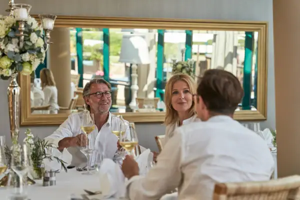 Wintergarten Eine Gruppe von Menschen sitzt an einem Tisch mit Weingläsern.