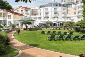 A-ROSA Heringsdorf Außengarten Liegestuhl im Garten mit Bäumen und klarem Himmel im Hintergrund.