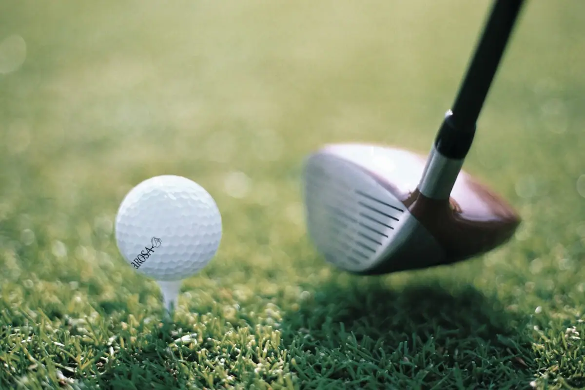 Ein Golfball auf einem Tee mit einem Golfschläger daneben.