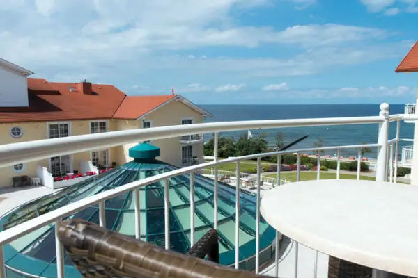 Ein Balkon mit Tisch und Stühlen mit Blick auf ein Gewässer.