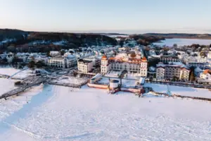 Kurhaus Binz Schneebedeckte Stadt mit Gebäuden und einem Gewässer im Winter.