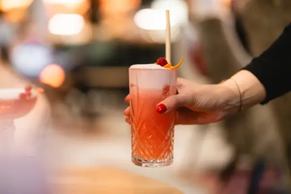 Eine Hand hält ein Glas mit einem Getränk.
