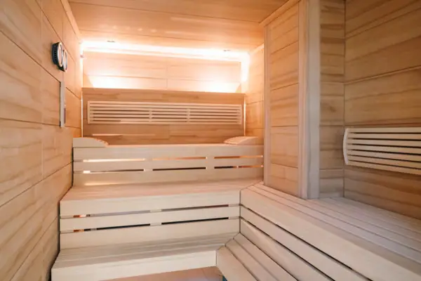 Sauna Eine hölzerne Sauna mit Bänken und einer Lampe im Hintergrund.