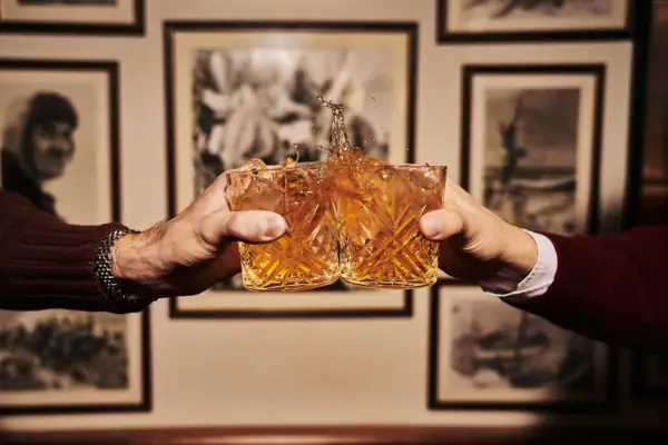 Zwei Hände halten Gläser mit spritzender Flüssigkeit.