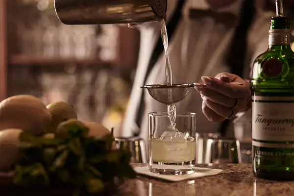 Eine Person gießt ein Getränk in ein Glas ein.