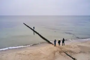 Strand Menschen am Strand mit einem Holzpfosten im Wasser