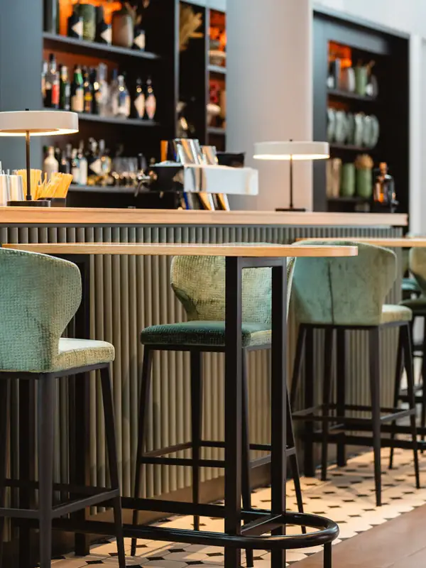 Bar auf Sylt Eine Bar mit grünen Stühlen und einem schwarzen Regal mit Flaschen.