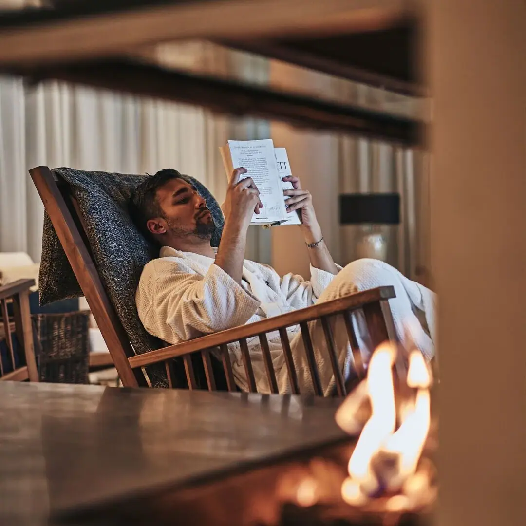 Ein Mann im weißen Bademantel liest ein Buch.