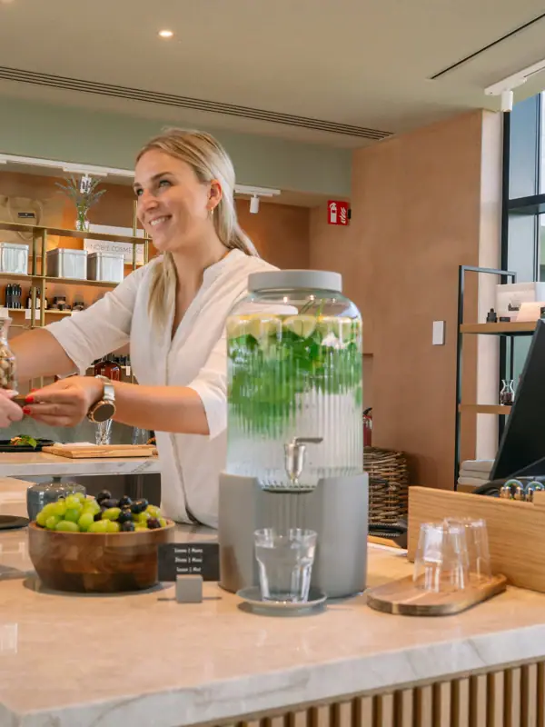 Eine Frau reicht einem Kunden ein Getränk.