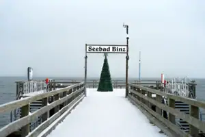Seebrücke Ein schneebedeckter Gehweg mit einem Weihnachtsbaum und einem Schild.