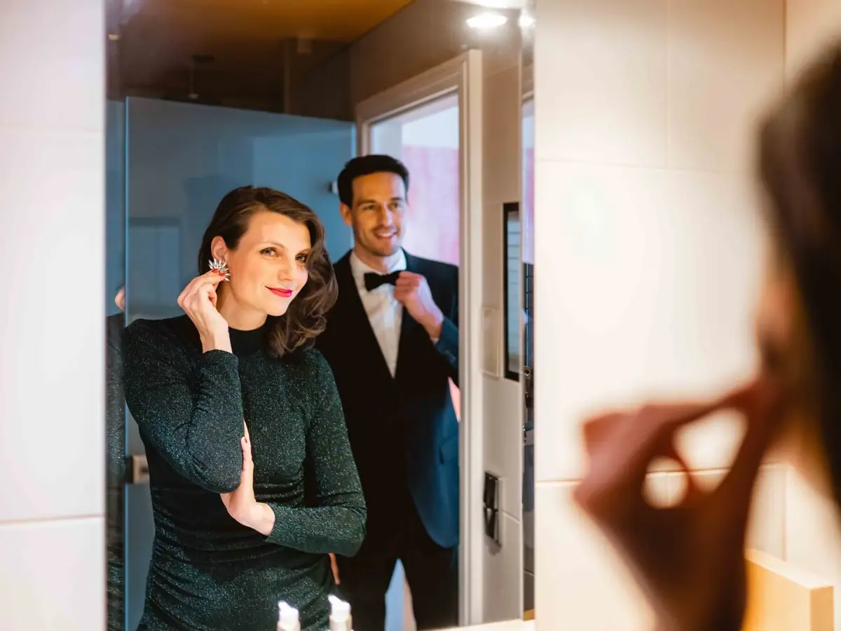 Styling für Silvester Ein Mann im Anzug und Frau, die Ohrringe anlegt.