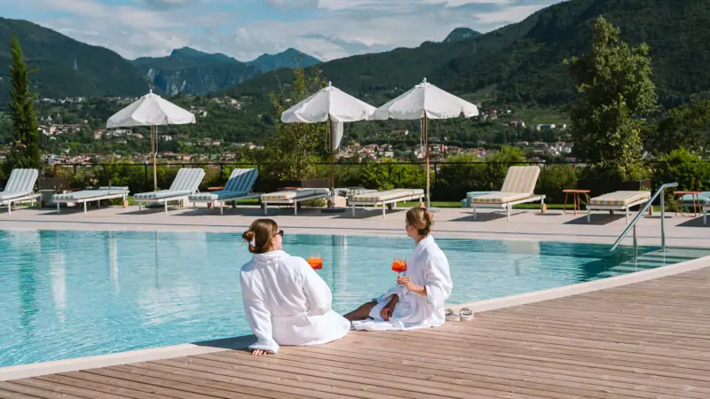 Zwei Frauen sitzen am Pool im Freien.