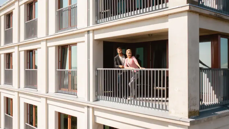 Ein Paar steht auf einem Balkon eines Gebäudes.