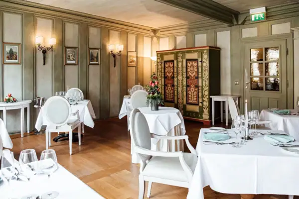 Bohlenstube Ein Raum mit Tischen und Stühlen, elegant eingerichtet mit Tischdecken und Geschirr.