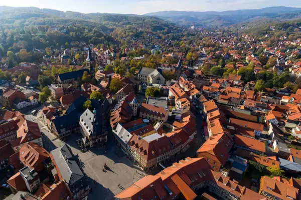 Wernigerode Luftaufnahme einer Stadt mit Häusern, Bäumen und Bergen im Hintergrund.