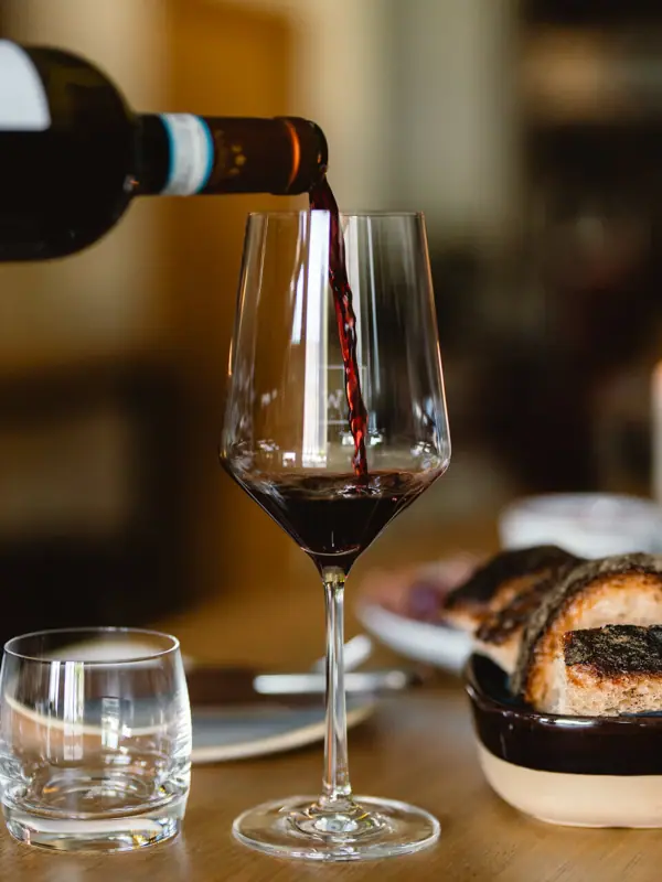 Eine Person schenkt Wein in ein Glas ein.