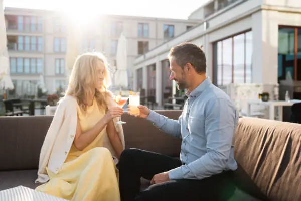 Ein Mann und eine Frau sitzen auf einem Sofa und halten Getränke.