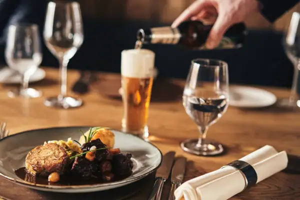 Eine Person schenkt ein Getränk in ein Weinglas ein.