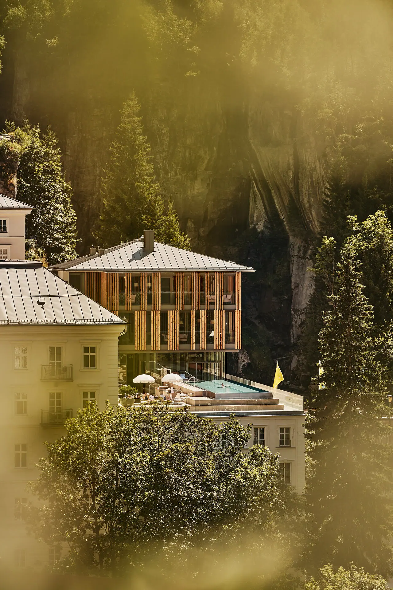 A-ROSA Bad Gastein Gebäude mit Pool in der Mitte, umgeben von Bäumen und Pflanzen.