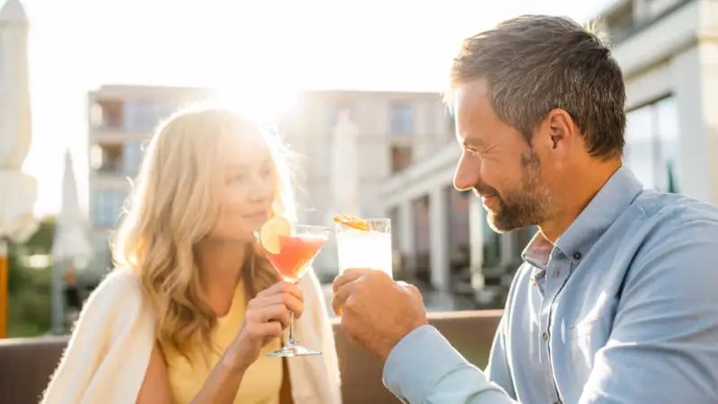 Terrasse A-ROSA Sylt Ein Mann und eine Frau halten Getränke.