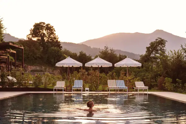 Eine Person in einem Pool mit Liegestühlen und Sonnenschirmen.