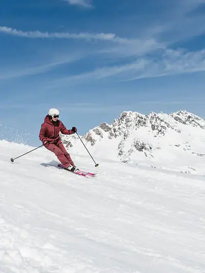 Eine Person fährt auf Skiern einen verschneiten Berg hinunter.