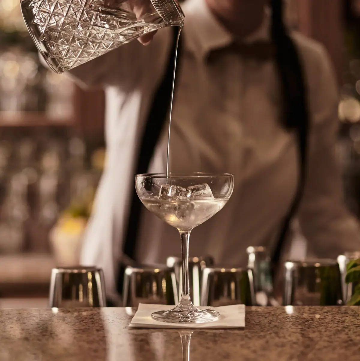 Eine Frau gießt eine Flüssigkeit in ein Weinglas ein.