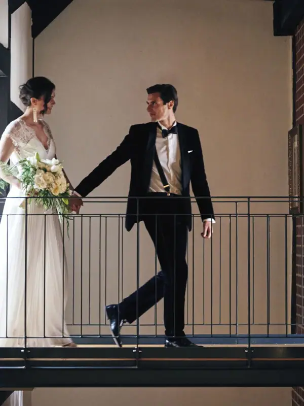 Ein Mann und eine Frau stehen auf einem Balkon in formeller Kleidung.