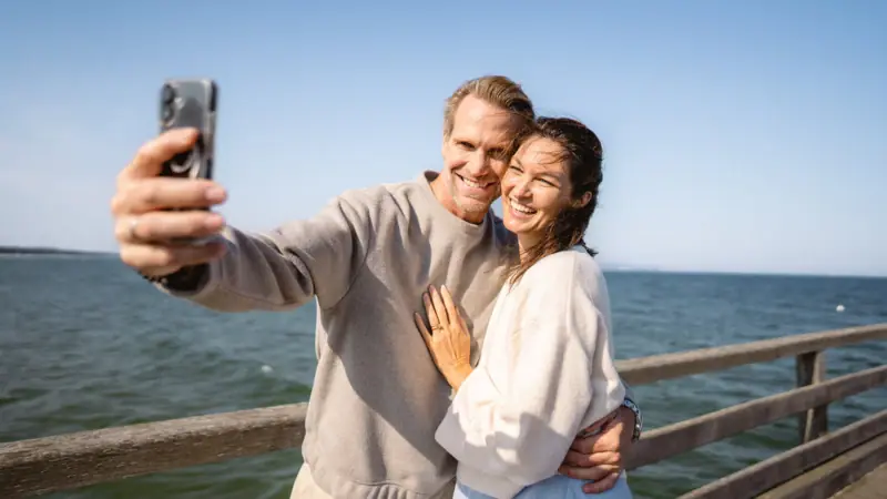 Paar am Strand Ein Mann und eine Frau machen ein Selfie im Freien.