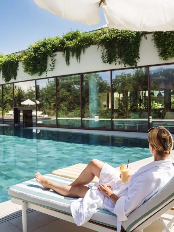 Eine Frau sitzt auf einer Sonnenliege am Pool.