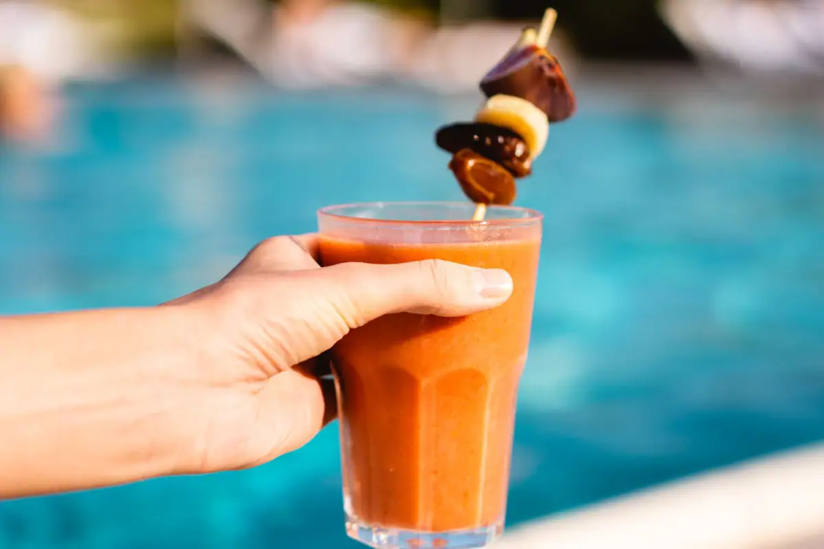 Eine Hand hält ein Getränk mit einem Strohhalm.