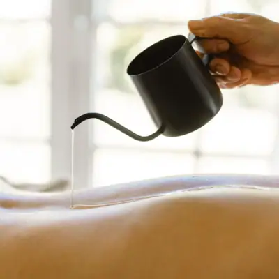 Eine Person gießt Öl auf einen Rücken.