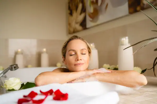 SPA-Suite im A-ROSA Sylt Einen Frau entspannt in einer Badewanne in einem Schaumbad und hat die Augen geschlossen.