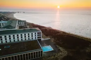 A-ROSA Sylt Ein Gebäude neben einem Strand bei Sonnenaufgang.